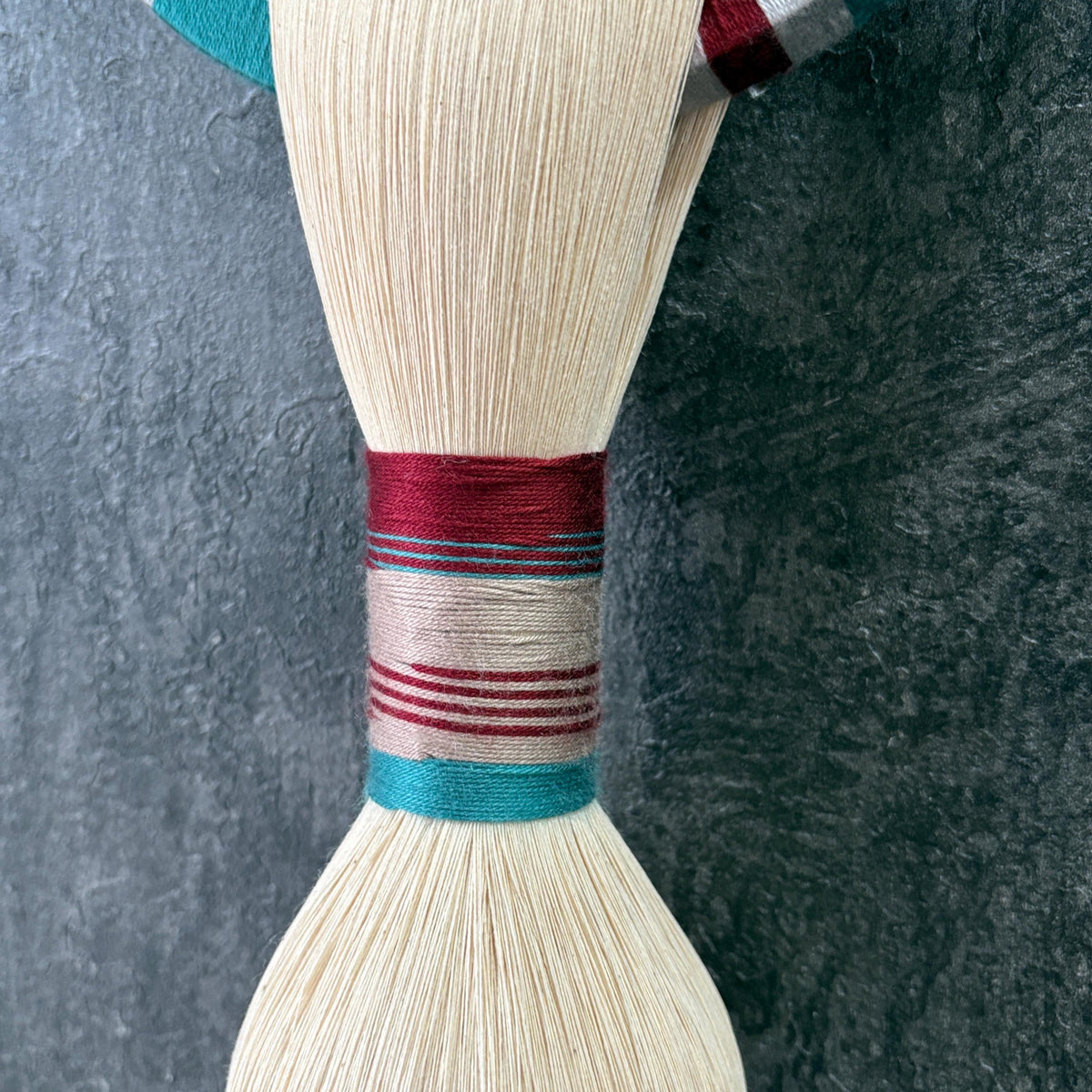 Burgundy, ivory and turquoise cord bindings around the cotton wall hanging