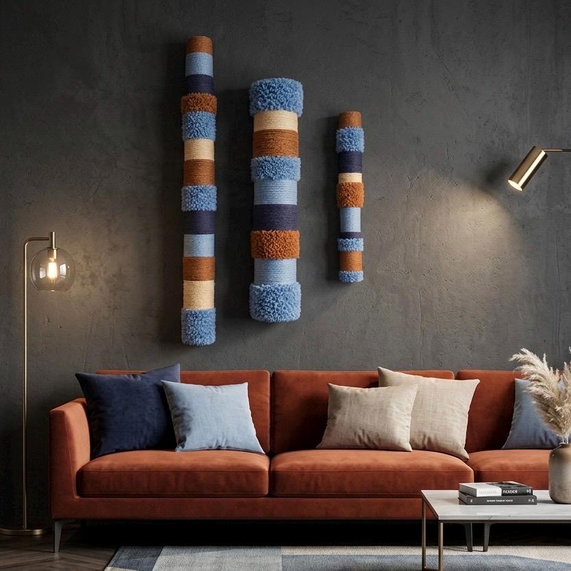 Blue and earth-tone fiber wall sculptures shown against a dark wall